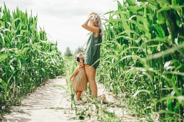 Szczęśliwa rodzina: Młoda piękna kobieta z jej małą śliczną córką chodzenie w polu kukurydzy — Zdjęcie stockowe