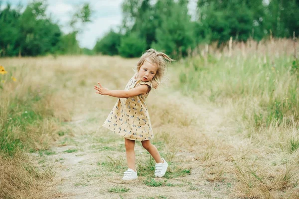Радостная маленькая девочка веселится на зеленой траве в руках на природе . — стоковое фото