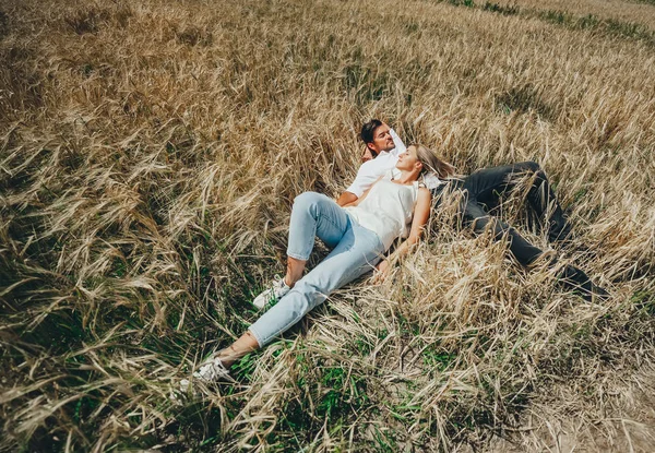 Χαρούμενο κομψό ζευγάρι που κείτεται στο χωράφι με το σιτάρι. — Φωτογραφία Αρχείου
