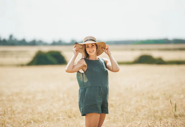 Feliz joven con sombrero de paja disfrutando del sol en el campo de trigo . — Foto de Stock