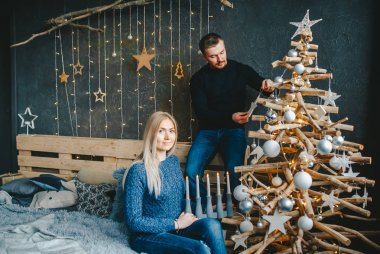 Aşk ta noel ağacını evde süsleyen, kışlık kazak giyen bir çift. Yeni yıla hazırlık.
