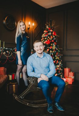 Onun kız ile noel dekore ağaç yakınında ahşap at salıncak yakışıklı adam