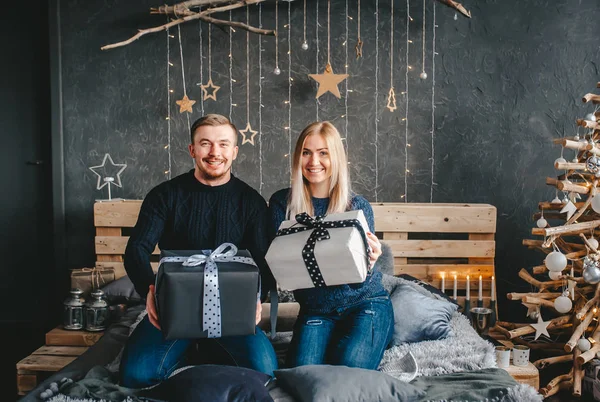 Familia joven con regalos de Navidad juntos. Vacaciones de Navidad. Pareja feliz sentada en la cama . —  Fotos de Stock