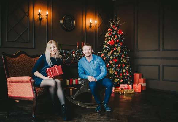 Счастливая пара, сидящая у елки в уютной темной гостиной в канун Рождества . — стоковое фото