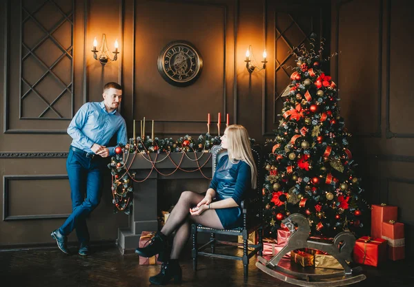 Mavi giysiler içinde Büyüleyici genç çift Noel ağacı ile bir odada pozlar