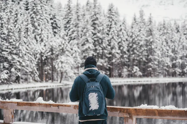 Jeden mężczyzna młody mężczyzna Hiker stoi przed jeziorem zimowym patrząc na Snowy krajobraz, widok z tyłu. — Zdjęcie stockowe