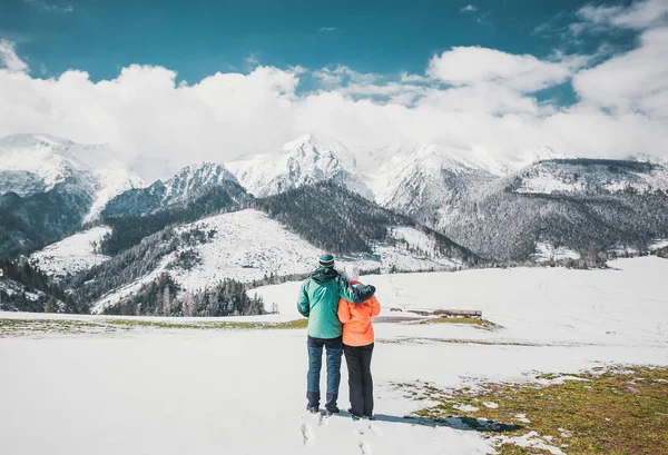 Casal amoroso de pé e olhando para belas montanhas nevadas picos. Vista panorâmica. Visão traseira . — Fotografia de Stock