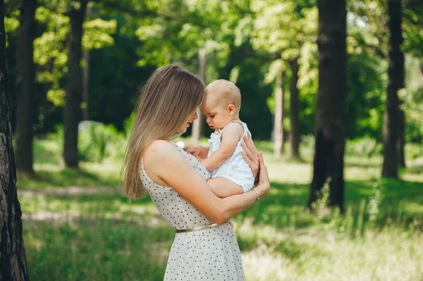 Vista frontal de mãe jovem com filha pequena em uma floresta de verão . — Fotografia de Stock