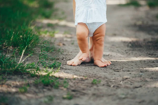 Baby macht erste Schritte mit der Hilfe der Mutter. Nahaufnahme. — Stockfoto