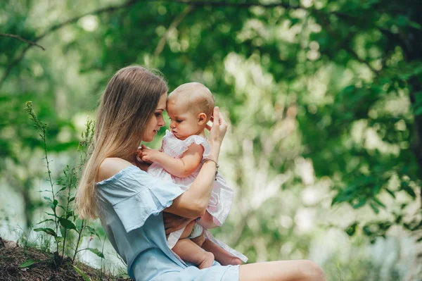 Mother and baby girl softly whispering face to face in the summer park. Side view. — Stock Photo, Image