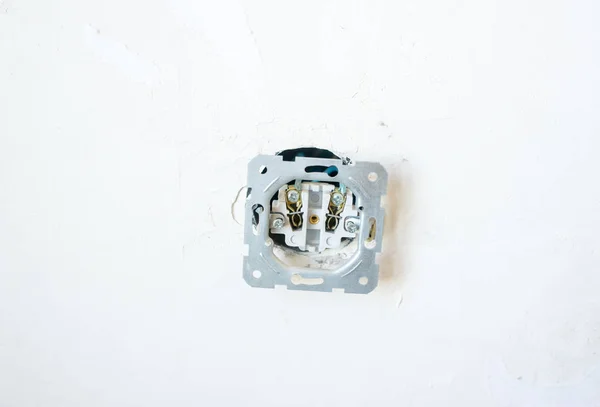 Old unsafe electric power point or socket on white cement wall background. Dangerous faulty plug.