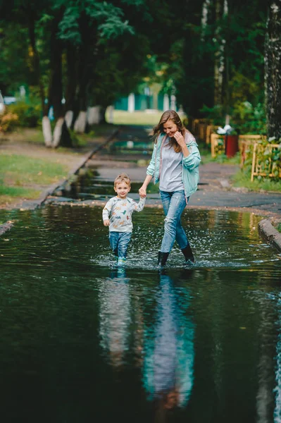 Familia feliz caminando en la calle después de una lluvia . —  Fotos de Stock