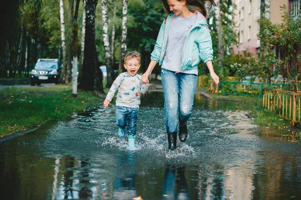 Child with his mother walking on the puddles after the rain. — Stock Photo, Image