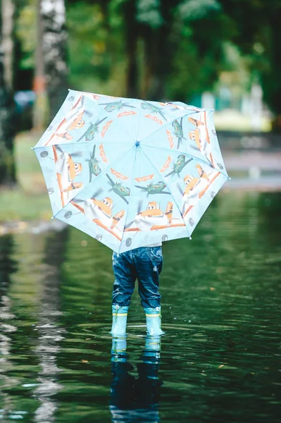 Kleine jongen verborg achter grote kleurrijke paraplu. — Stockfoto