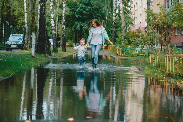 Joven madre con hijo pequeño caminando en la calle después de una lluvia . —  Fotos de Stock