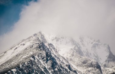 Slovakya'da dağ zirvesi manzarası. Kış karla kaplı dağlar ve çıplak kayalarla dolu alçak bulutlar.