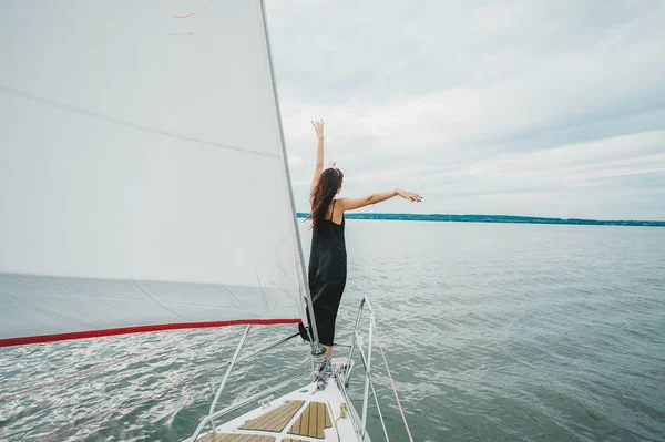 Young happy woman rising hands up on boat deck sailing the sea.