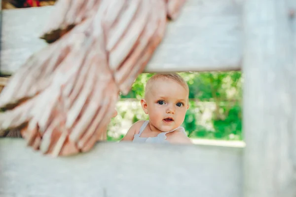 Retrato de cerca de la cara difícil de la niña escondida detrás de una cerca de madera . —  Fotos de Stock
