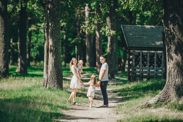 Lyckligt ungt par spenderar tid med sina döttrar i naturen. — Stockfoto