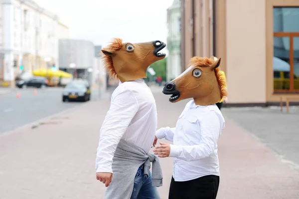 Casal usando máscaras de cavalo abraça na rua da cidade . — Fotografia de Stock