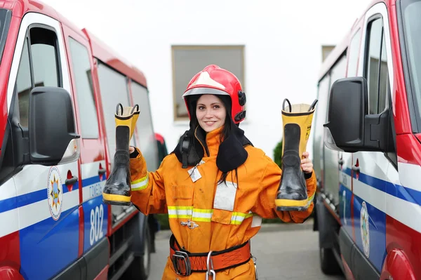 Felice pompiere donna in casco sta accanto a un camion dei pompieri — Foto Stock