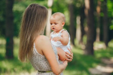 Mutlu anne ve bebeğinin yaz ormanındaki portresi.
