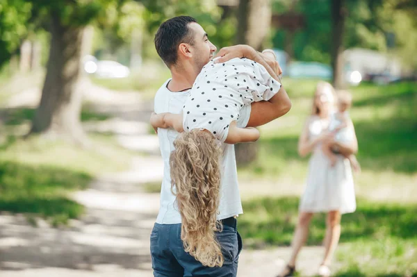 Alegre padre y encantadora hija actividad al aire libre. Feliz padre sostiene su adorable bebé de cabeza en el parque de verano —  Fotos de Stock