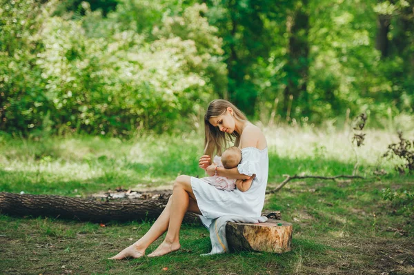 Mother breastfeeding her baby on a sunny day in a green meadow — Stock Photo, Image