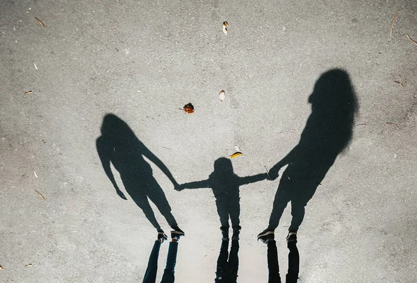 Silhouettes, shadow of a family on the pavement.