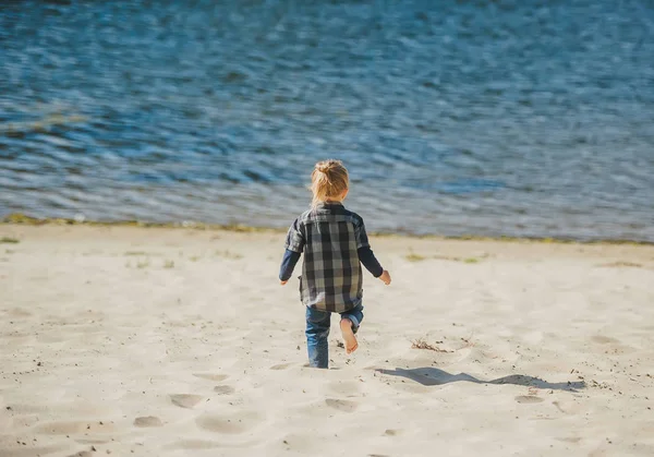 Lindo niño corriendo en la playa de arena. Vista trasera —  Fotos de Stock