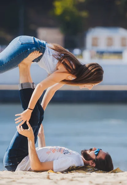 Liefdevolle paar doen yoga oefeningen samen op het zandstrand. — Stockfoto