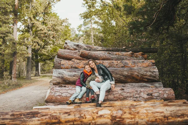 Mor och hennes barn tittar i höstskogen på en vedstapel — Stockfoto
