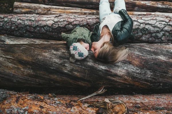 Otoño retrato de la madre y la niña besándose en la pila de troncos . — Foto de Stock