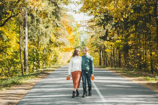 Sonbahar renkli parkta asfalt yolda yürüyen güzel bir çift. — Stok fotoğraf