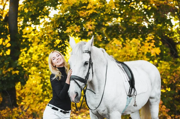 Söt blond kvinna med vit häst i höst natur. — Stockfoto