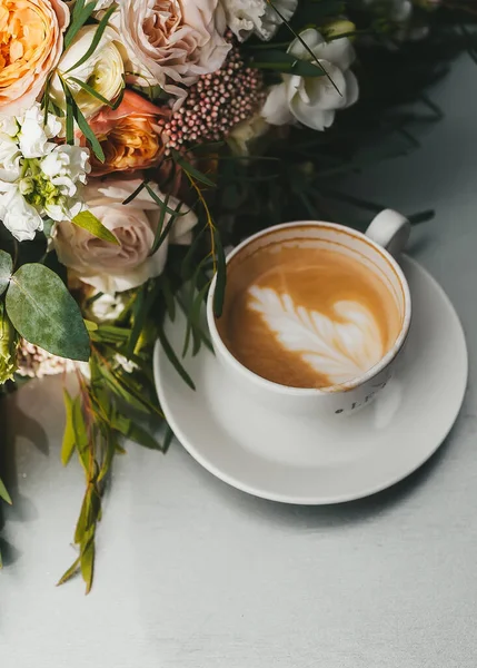 コーヒーを飲みながらテーブルの上でバラの結婚式の花束 — ストック写真