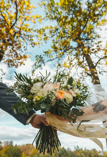 Buquê de casamento com rosas amarelas em um fundo de árvores de outono e céu azul em dia ensolarado — Fotografia de Stock