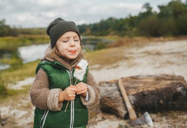 Doğada piknik yaparken marşmelov yiyen tatlı bir kız. Sonbaharda çocuklarla aile eğlencesi..