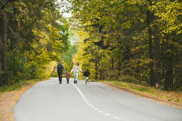 Mama, tata i małe dzieci, spacerujące wiejską drogą. Rozmawiają i cieszą się pięknym jesiennym dniem.. — Zdjęcie stockowe