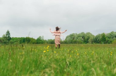 Baharda sarı karahindibalarla güzel çayırlarda dinlenen mutlu bir kadın. Arka plan