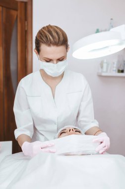 Master müşterisi için kozmetik bir işlem yapıyor. Cilt bakımı. Kadın yüz bakımı prosedürü uyguluyor. Profesyonel yüz bakımı kavramı