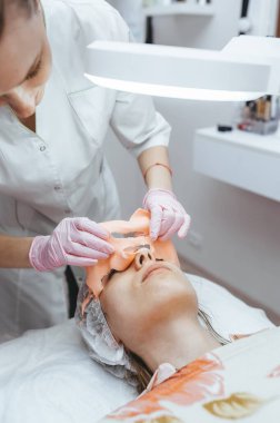 Güzellik uzmanı, hastanın yüzüne yaşlanma karşıtı aljinat maskesi takıyor. Profesyonel yüz bakımı kavramı