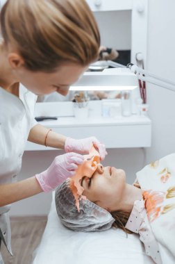 Profesyonel bir güzellik uzmanı hastasına yaşlanmayı önleyici bir maske takar.