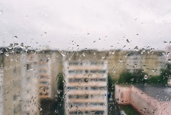 雨水落在窗玻璃的表面上 映衬着一幢多层楼房的背景图 雨滴的结构 — 图库照片