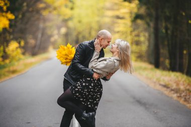Aşık genç bir çift. Sarışın kadın ve yakışıklı kel adam güneşli bir havada sonbahar asfalt yolunda yürürken kucaklaşıyorlar. Aşk, ilişki, insanlar. Yakın plan portre