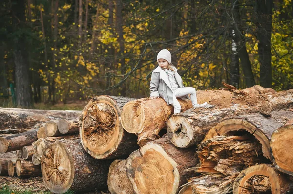 Mała Dziewczynka Siedzi Stercie Kłód Ubrana Ciepłe Ubrania Biały Kapelusz — Zdjęcie stockowe