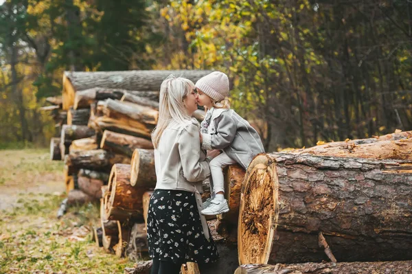 Wonderful Mother Kissing Her Small Daughter Background Stacked Logs Background — Stock Photo, Image