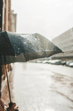 Akşam yağmuru ve siyah şemsiye, ıssız bir şehir sokağının arka planında. Yakın görünüm.