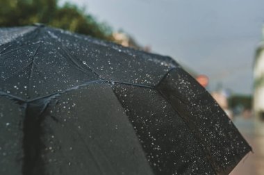 Siyah şemsiye yüzeyine düşer. Şehirde yağmur sırasında şemsiyeli insanlar. Yağmur günü. Yakın görünüm.