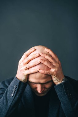 Kafasını kameraya çevirmiş hayal kırıklığına uğramış kel bir adam. Karanlık arka planda izole edilmiş. Dikey görünüm